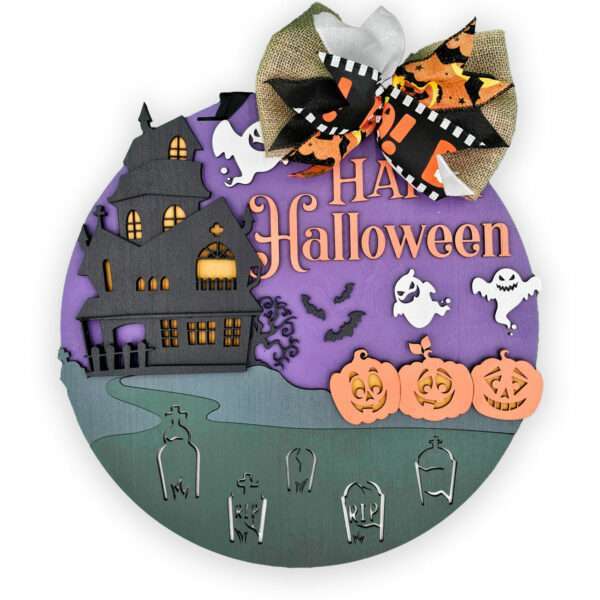 A round Halloween decoration featuring a haunted house, two ghosts, three jack-o'-lanterns, and gravestones. The top half is purple with the text "Happy Halloween" and a black, orange, and white ribbon bow at the top. The bottom half is green with gray gravestones.