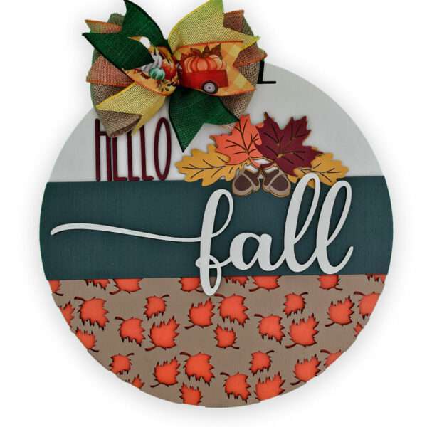 A custom door sign for fall featuring a colorful bow adorned with pumpkins, leaves, and corn on top. The round board reads "Hello Fall" and is decorated with acorns and autumn leaves. The bottom section is beautifully patterned with orange and red foliage, perfect for welcoming the season.