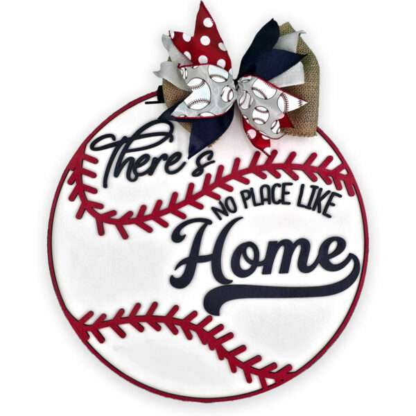 A circular sign designed to resemble a baseball with red stitching, featuring the heartfelt text "There's no place like home" in black cursive. Adorned with a decorative bow made of red polka dot, baseball pattern, and burlap ribbons at the top.