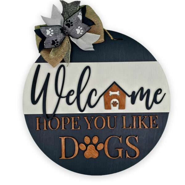 A circular wooden sign with a burlap and ribbon bow at the top reads, "Hope You Like Dogs." A small doghouse graphic and paw prints are integrated into the design, adding charm. The text is in black and brown on a white and dark blue background.