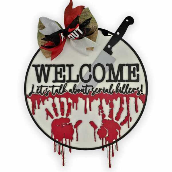 A round sign with a decorative bow and a cleaver attached. Text reads, "WELCOME Let's talk about serial killers!" Below the text are red handprints and red drips resembling blood. Perfect for Halloween, the bow is black, white, and red. The cleaver is silver with a black handle.