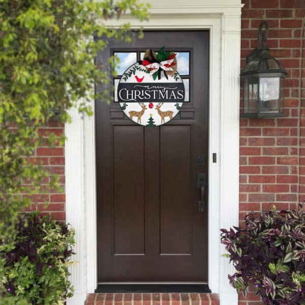 A dark brown front door with a festive Christmas wreath hanging in the center. The wreath features merry reindeer, trees, and a "Merry Christmas" message, adorned with red and white flowers and a bow. The surrounding area includes brick walls and potted plants.