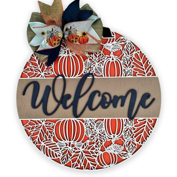 A custom door sign, this round autumn-themed welcome piece features intricate cutouts of pumpkins and leaves. The base layer is a flat orange design with prominent white pumpkin and leaf details. The word "Welcome" is displayed in cursive, topped by a decorative bow in fall colors.